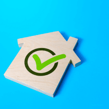wood cutout house with green check mark